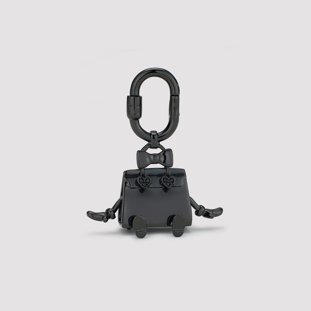 Black keychain shaped like a small bag with a bow on a light gray background
