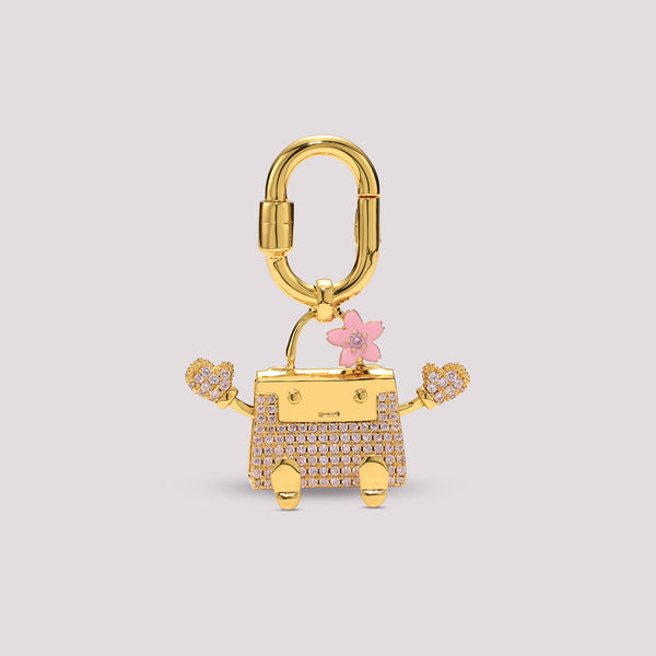 Gold Kelly Doll charm shaped like a robot with a pink flower on a light gray background