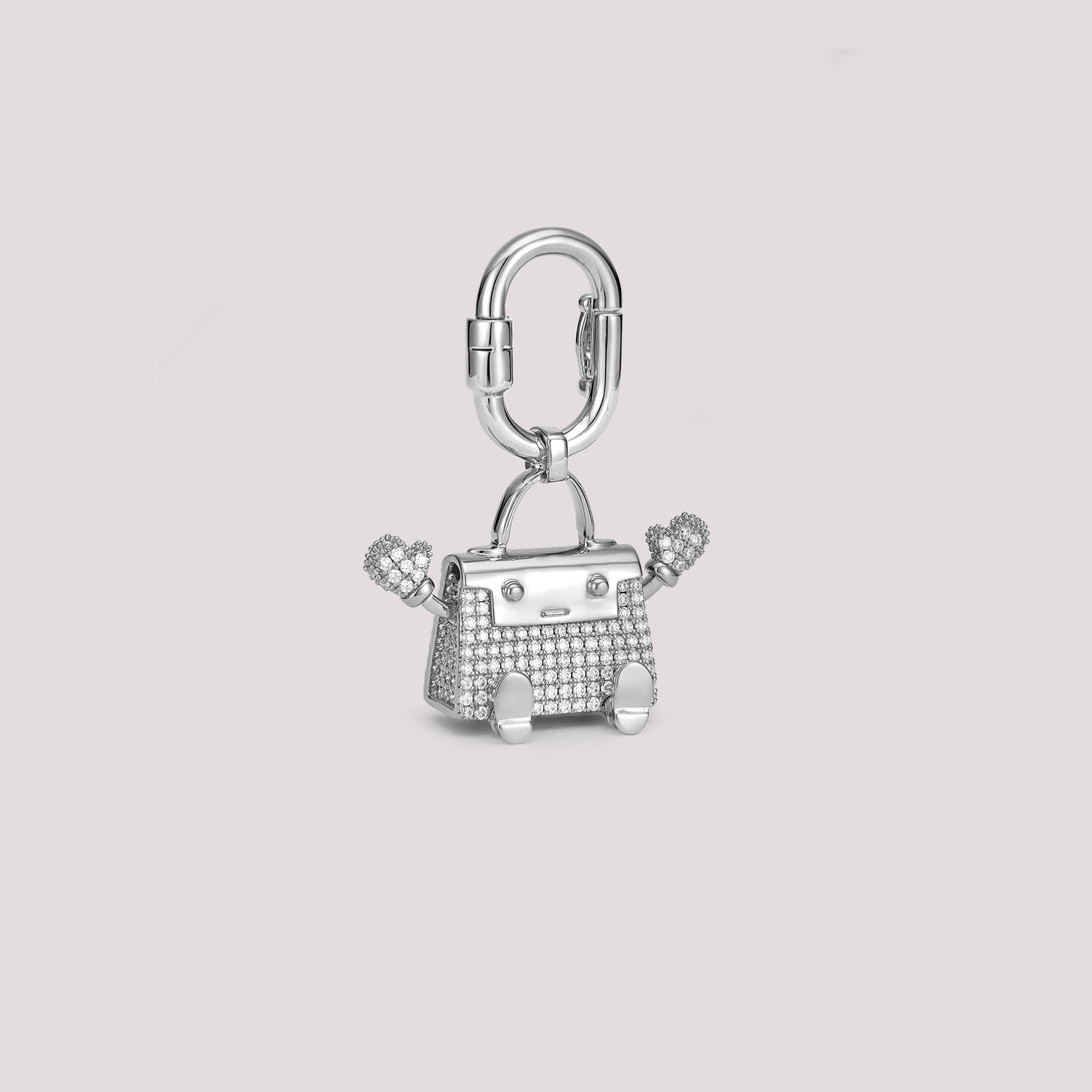 The Baby Kelly Doll Bag Charm stands out with its two playful waving arms. It has hand-set pavé stones and cute doll-like legs. Every stone is carefully placed, and the miniature handbag design reflects the essence of timeless luxury. This charm is a great addition to your Hermès collection or any luxury handbag. It adds a unique and charming touch to your style.