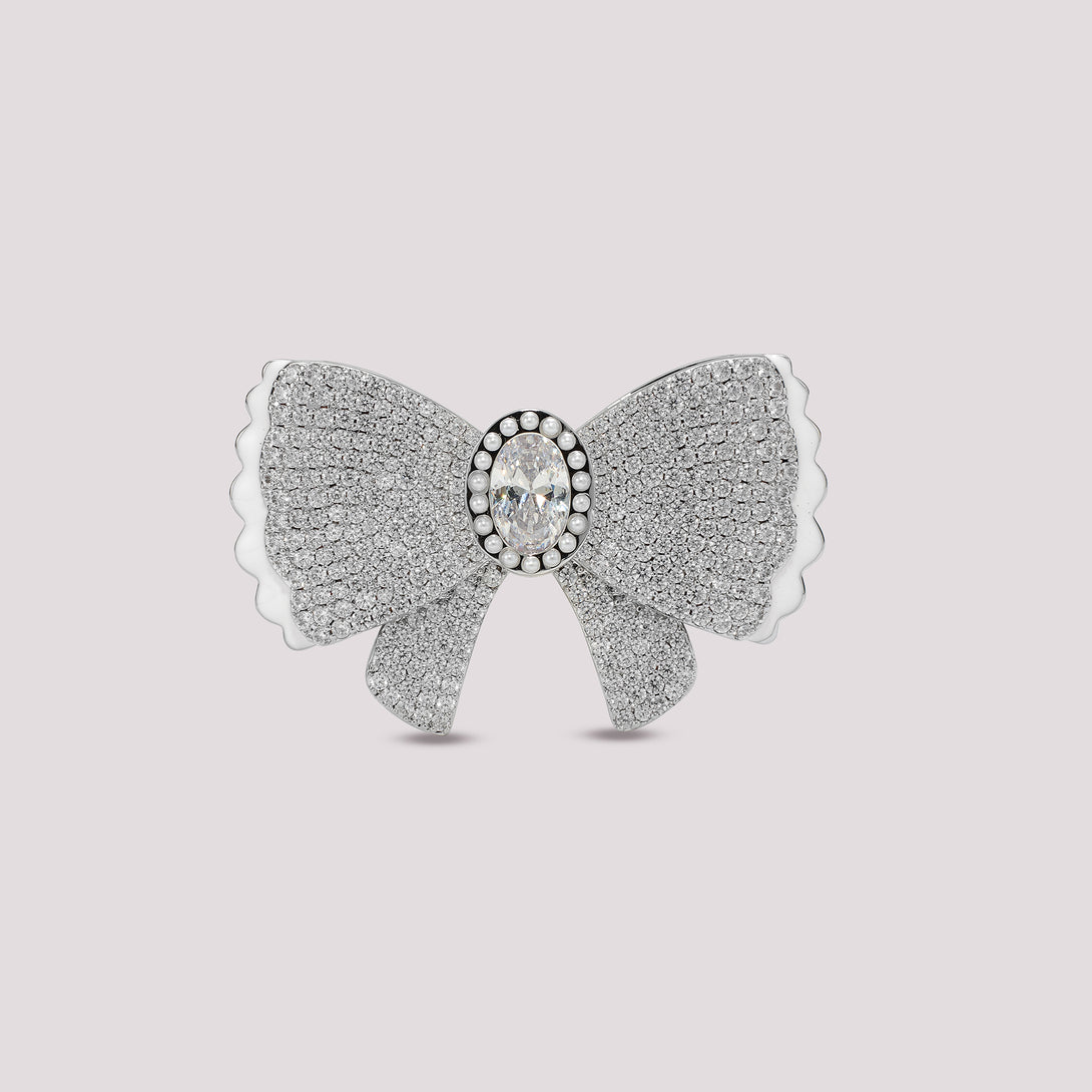 Silver bow-shaped bag charm with a central gemstone on a light gray background