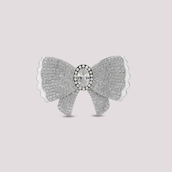 Silver bow-shaped bag charm with a central gemstone on a light gray background