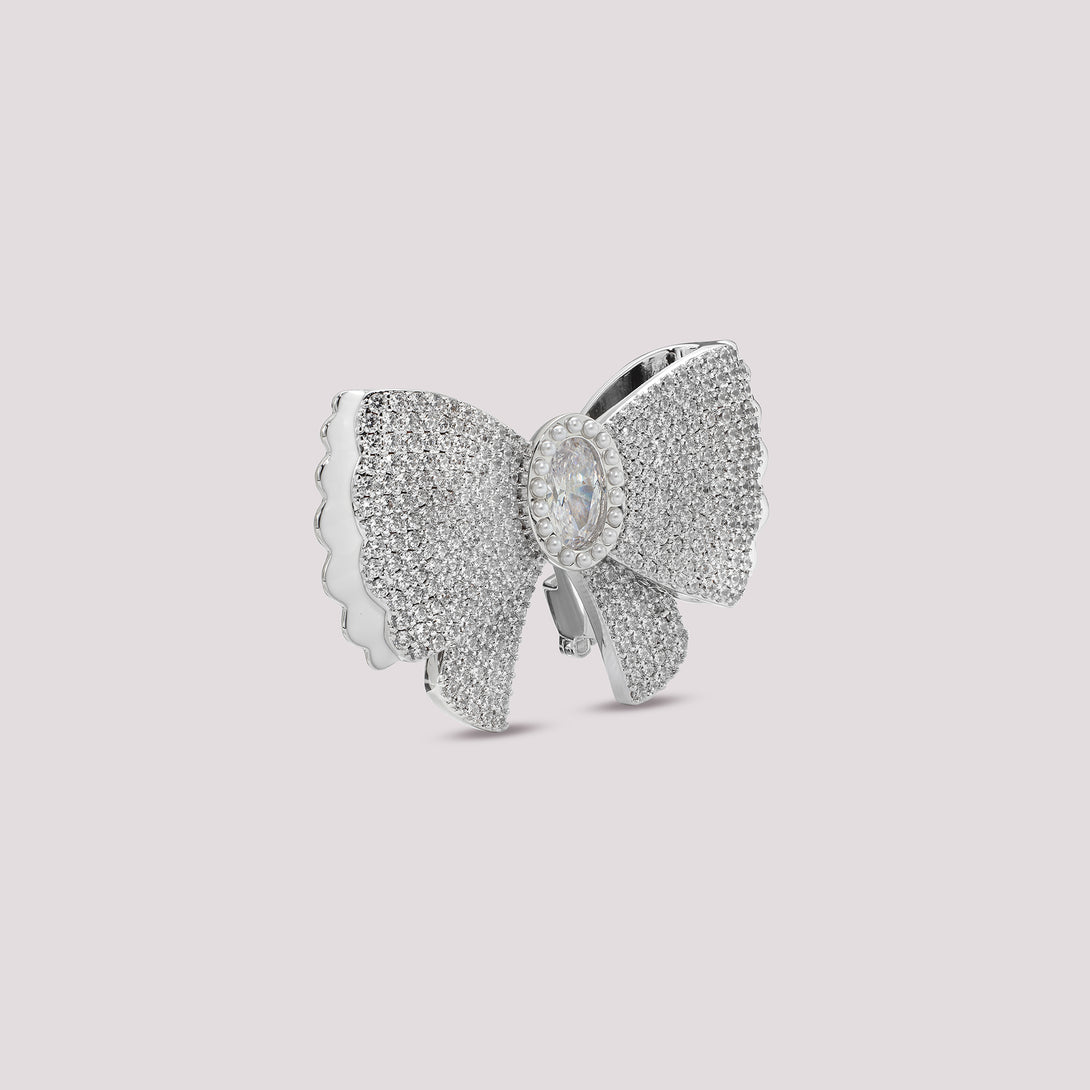 Silver bow-shaped bag charm with clear stones on a light gray background