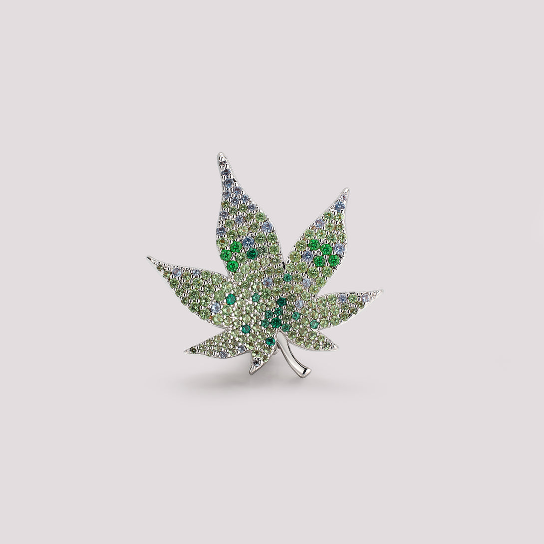 Decorative maple leaf bag charm with gemstones on a light gray background