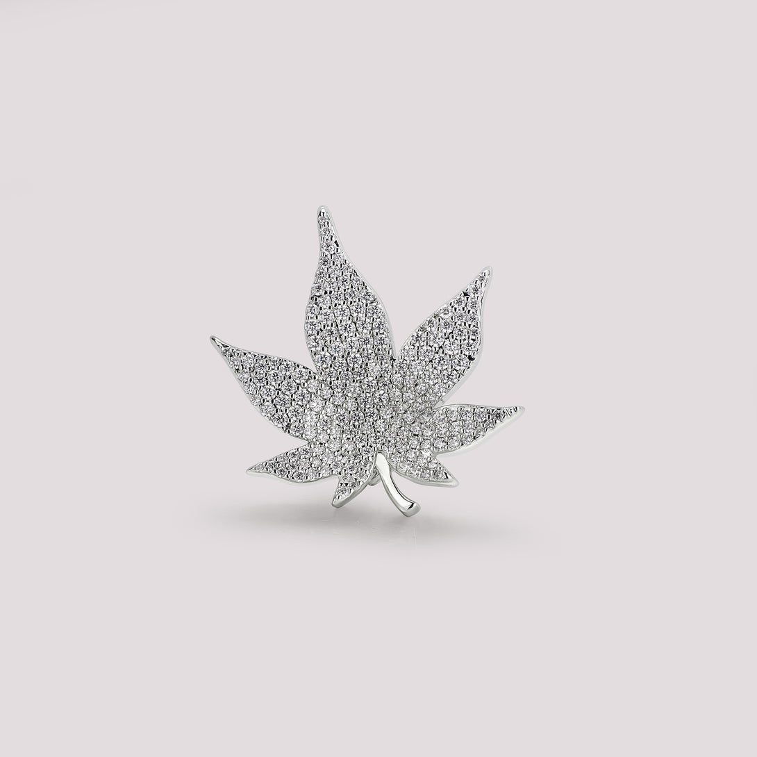 Silver leaf-shaped bag charm jewelry piece on a light gray background